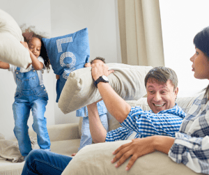children in pillow fight with dad in the living room