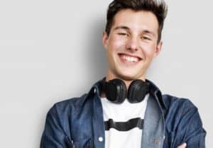 young teen boy with denim shirt and headphones smiling happy