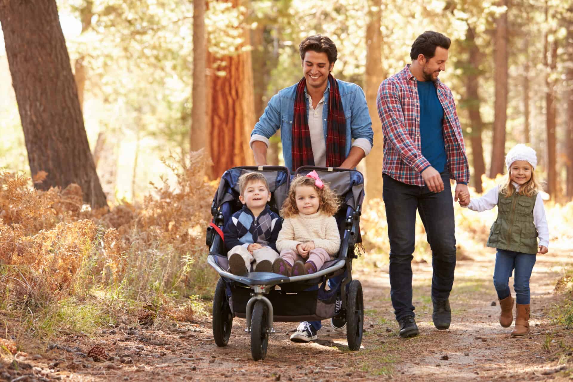 two foster carer dads with their 3 children walking in the woods