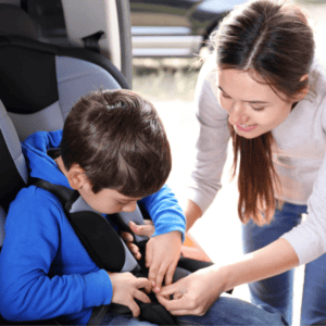 foster mum and child fastening child into car seat safely