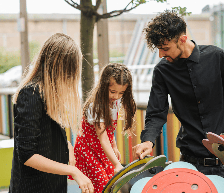 Foster carer man and woman with girl child at play exhibit