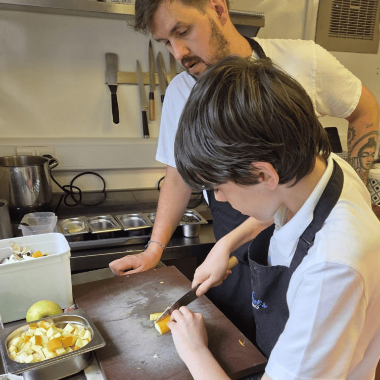 Michael patron of The Foster Care Charity showing child how to cook at his bistro